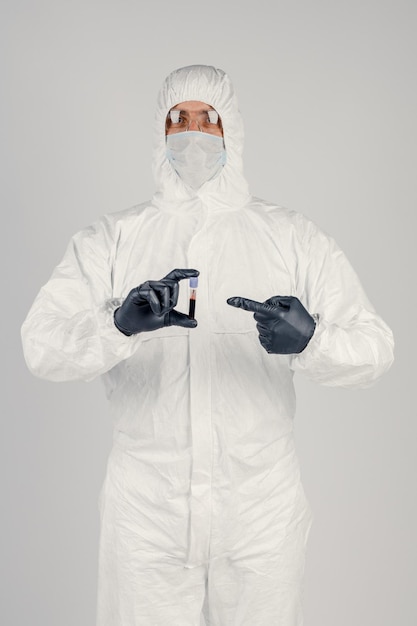 A test tube in a man's hand closeup a man in a medical mask holding a bottle of red liquid Concept of blood samples medical and chemical research