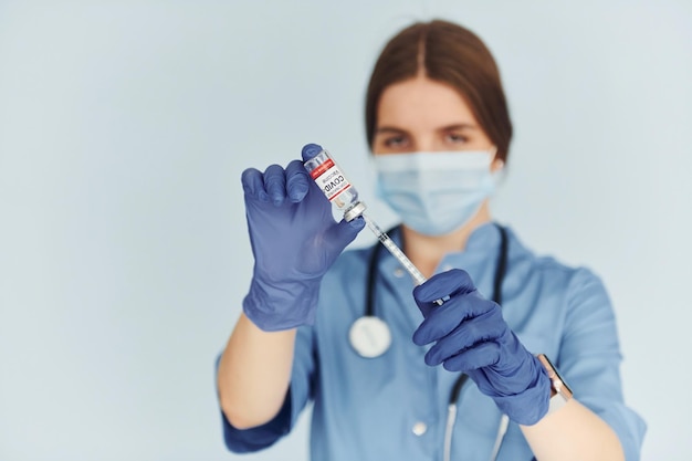 Test tube with vaccine Young female doctor in uniform is indoors