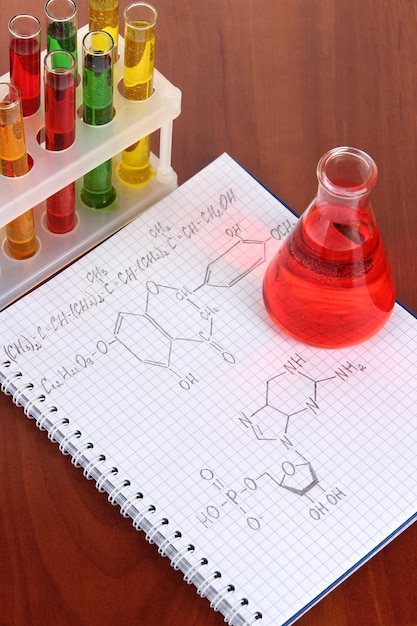 Test tubes with colorful liquids and formulas on table