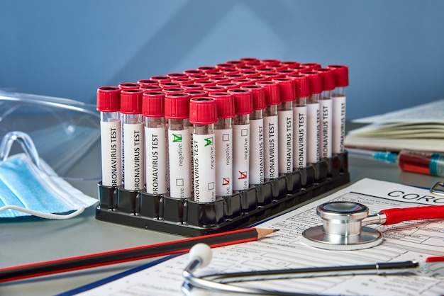 Photo test tubes with positive and negative blood samples for covid-19 next to the coronovirus test form.