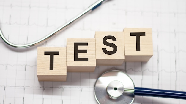 Test word written on wooden blocks and stethoscope on light white background