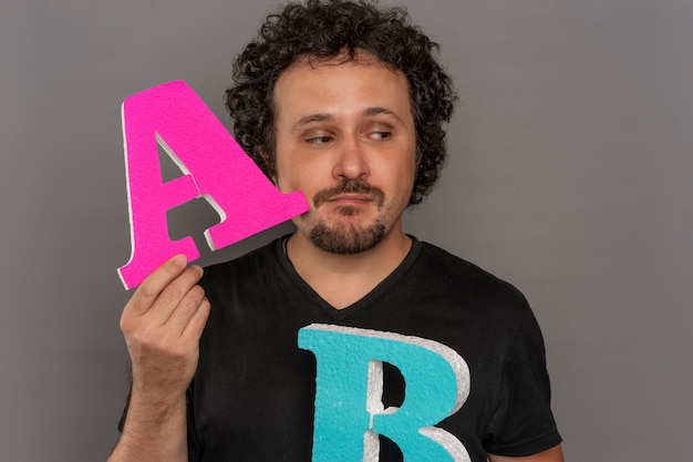 Testing, conversion funnel, A / B test in marketing and online advertising. Brunette man holding colored letters A and B in hands with face expressions