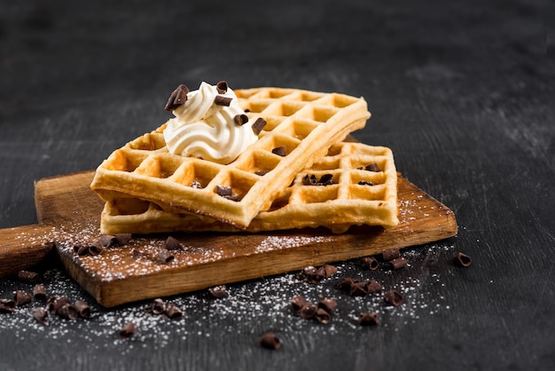 Testy homemade waffles with cream on the black wooden background