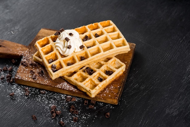 Testy homemade waffles with cream on the black wooden background