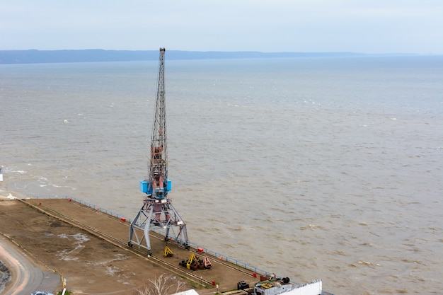 Tetyushi, Tatarstan / Russia - May 2, 2019: Top view of the empty industrial pier with cargo harbor crane on the dock along spacious Volga River. Inland navigation is not claimed and not used.