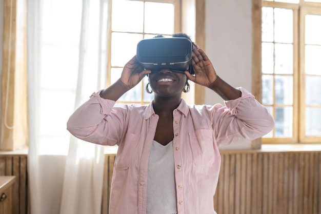 Tevreden Afrikaanse vrouw in roze kleren in VR-galsses