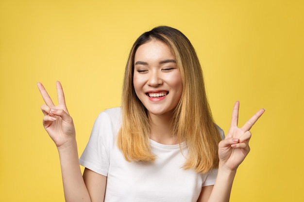 Tevreden Aziatische vrouw in t-shirt die vredesgebaren tonen