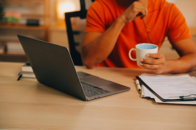 Tevreden blanke succesvolle man freelancer of CEO ontspant zich op de werkplek met benen op tafel stijlvolle man gebruikt laptop surft het internet zoekt naar ideeën voor een project zit aan het bureau