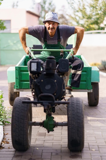 Tevreden boerenportret zittend achter het stuur van een tweewielige tractor