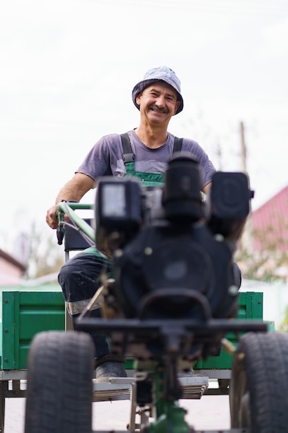 Tevreden boerenportret zittend achter het stuur van een tweewielige tractor