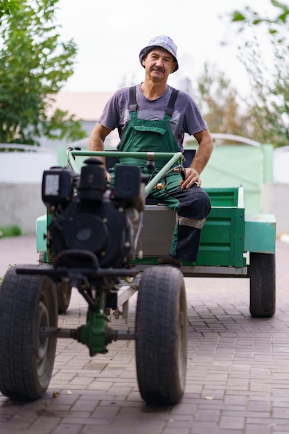 Tevreden boerenportret zittend achter het stuur van een tweewielige tractor