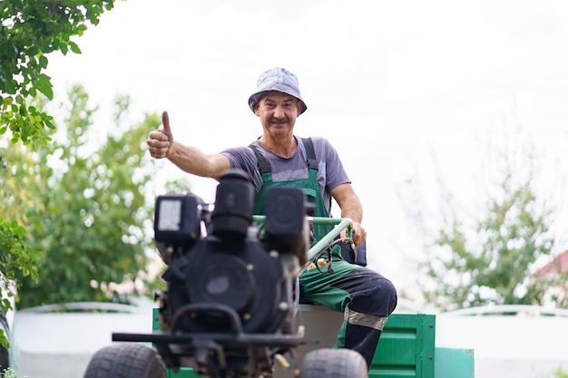 Tevreden boerenportret zittend achter het stuur van een tweewielige tractor