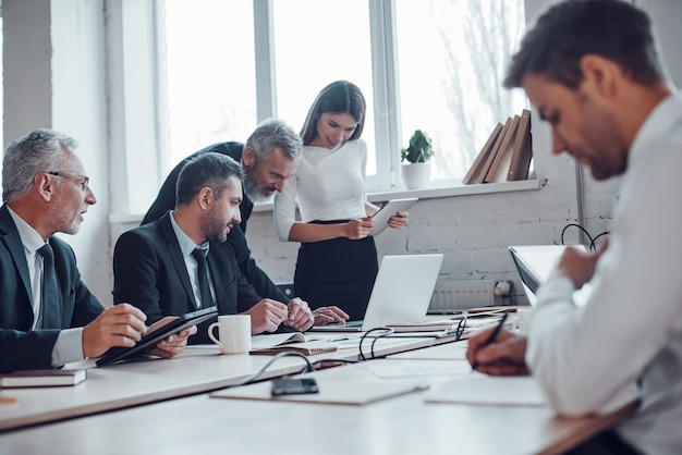 Tevreden collega's die bedrijfsuitbreiding bespreken terwijl ze samenwerken in het moderne kantoor