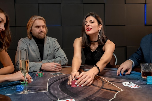 Tevreden jonge brunette die pokerspel wint in casino dat fiches op tafel harkt