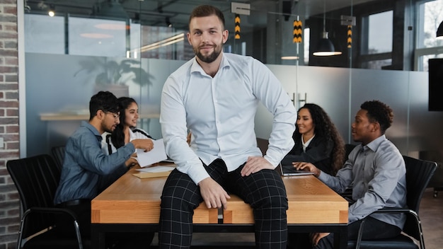 Tevreden man mannelijke leider baas bedrijf ceo zakenman zittend op tafel bureau in kantoor glimlach naar