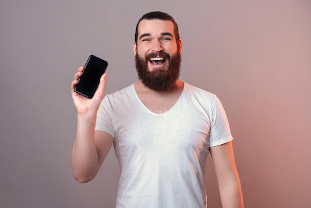 Tevreden man toont aan de camera het lege scherm van de telefoon die hij vasthoudt