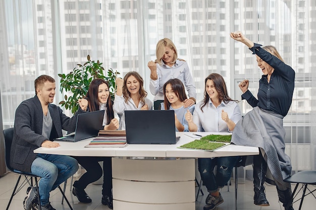 Tevreden met het verrichte werk en vol emoties gelukkige werknemers die het project aan tafel hebben voltooid en naar de laptopmonitor op kantoor hebben gekeken. Vreugde concept