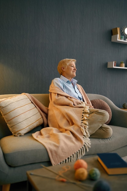 Tevreden oude vrouw gewikkeld in deken ontspannen