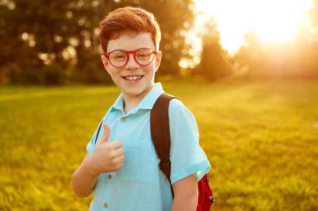 Tevreden schooljongen die een leuk teken in park laat zien