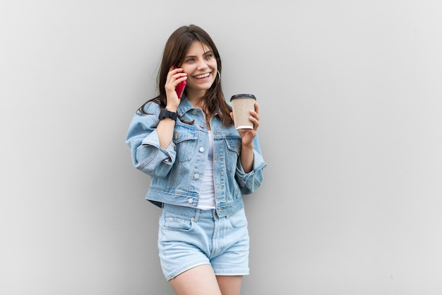 Tevreden vrouw die rust heeft op het werk, koffie drinkt om te gaan en met vriendje praat op mobiele telefoon