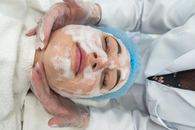 Tevreden vrouw maakt gebruik van de diensten van een professionele schoonheidsspecialist in een schoonheidssalon of spa