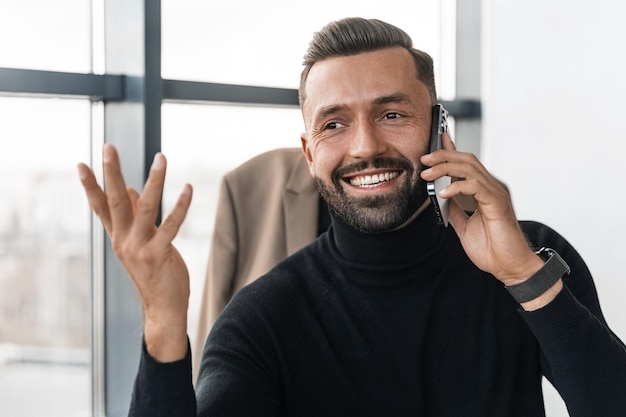 Tevreden zakenman praten op mobiele telefoon en gebaren