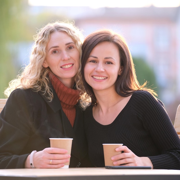 Tevreden zakenvrouwen die samen praten tijdens een koffiepauzebijeenkomst in een stedelijk straatcafé vriendschap tussen zakenpartners concept