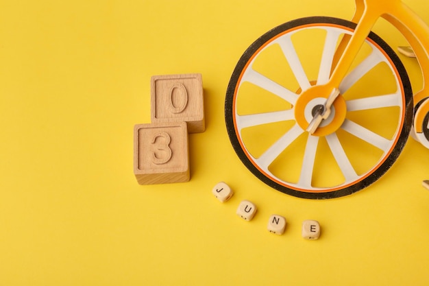 Text 03 june and small toy bicycle on yellow background Concept of Bicycle day Car free