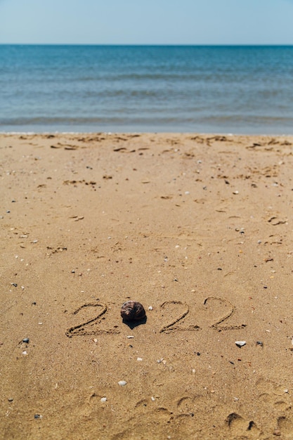 Text 2022 Written on the Sand of a Beach. The Sea on a Background of Letters