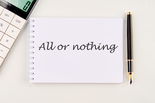 text ALL OR NOTHING on a white notebook