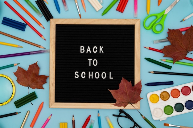 Photo text back to school soon on a wooden letter board buying stationery flatlay bright background maple leaves autumn school fees