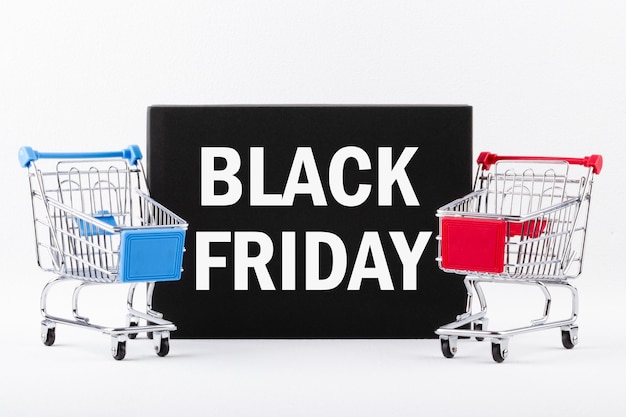 두 개의 쇼핑 카트 옆에 있는 블랙 보드에 BLACK FRIDAY라는 문자 할인 및 판매 개념