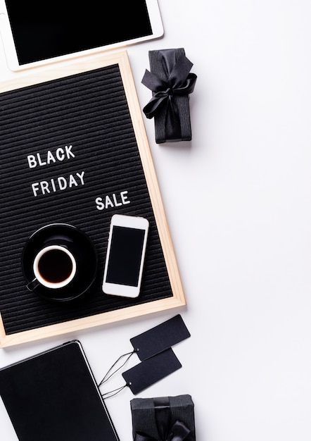text black friday sale on black letter board with cup of coffee, smartphone, price tags