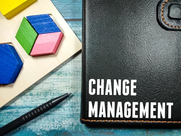 펜과 색색의 나무 블록이 있는 노트북에 쓰여진 텍스트 CHANGE MANAGEMENT