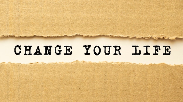 Foto testo cambia la tua vita che appare dietro carta marrone strappata