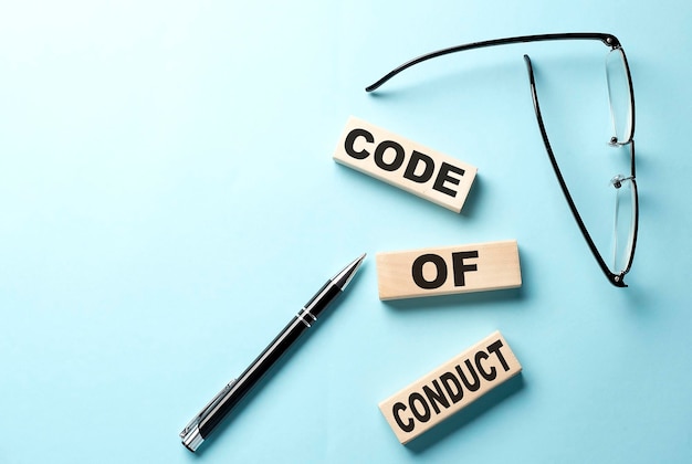 파란색 배경에 있는 나무 블록에 대한 CODE OF CONDUCT 개념 텍스트