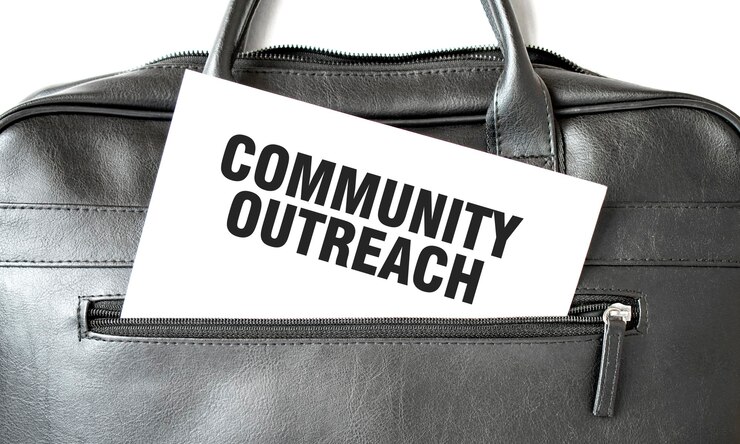 Photo コミュニティ・アウトリーチ (community outreach) は白い紙に書かれたテキストで黒いビジネスバッグに書かれているビジネスコンセプトです