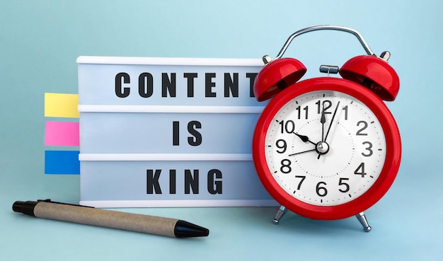 Text Content Is King written on the lightbox with alarm clock and colorfull stickers on blue background