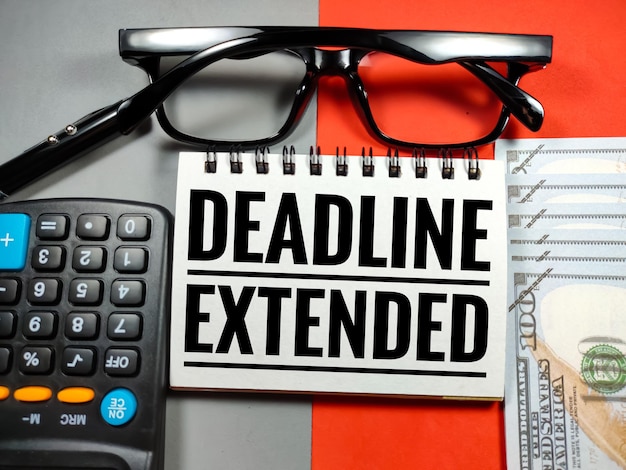 Text DEADLINE EXTENDED with glassescalculatorpen and banknote on gray and red background