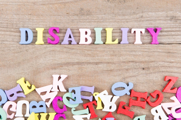 Text Disability of colored wooden letters on a wooden background