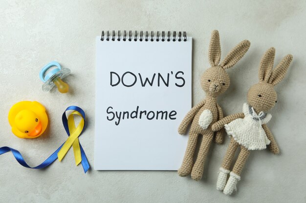 Text down's syndrome, toys, pacifier and awareness ribbons on white textured