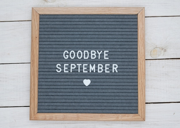 Text in English goodbye September and a heart sign on a gray felt Board in a wooden frame.