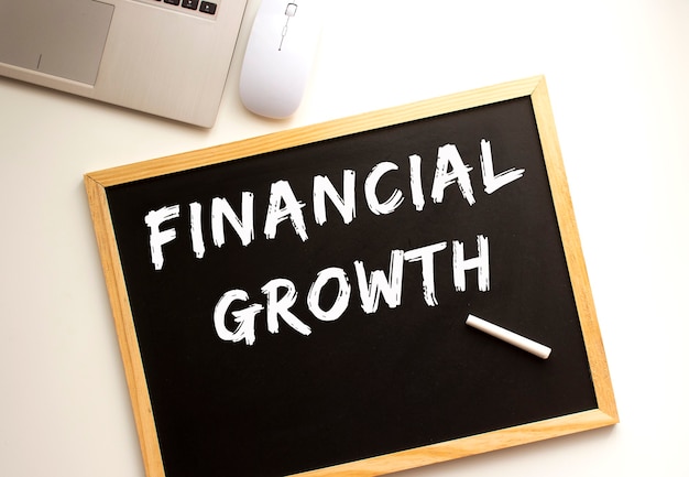 Text FINANCIAL GROWTH written in chalk on a slate board.