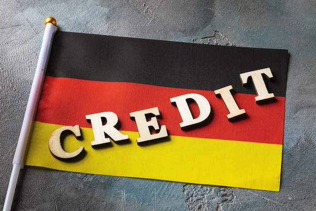 Текст из деревянных букв и немецкий флаг на абстрактном фоне концепции кредита из германии