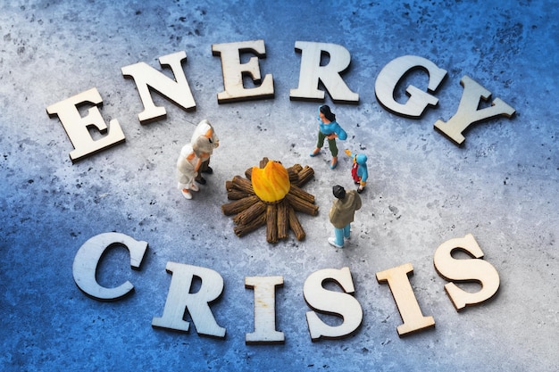 Текст из деревянных букв и игрушечных пластиковых человечков концепция на тему энергетического кризиса