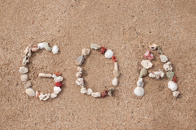 Text GOA made from shells on seashore on sandy beach