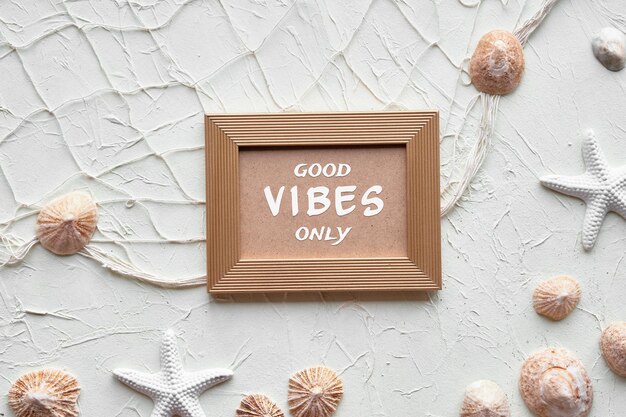 Text Good Vibes only in golden frame Off white background with starfish shells seashells necklace