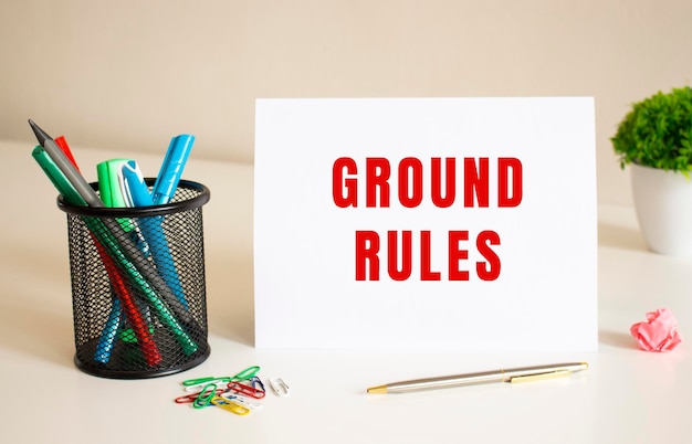 「GROUND RULES」というテキストは、テーブルの上にある白い折り紙に書かれています 近くにはペンと鉛筆があります