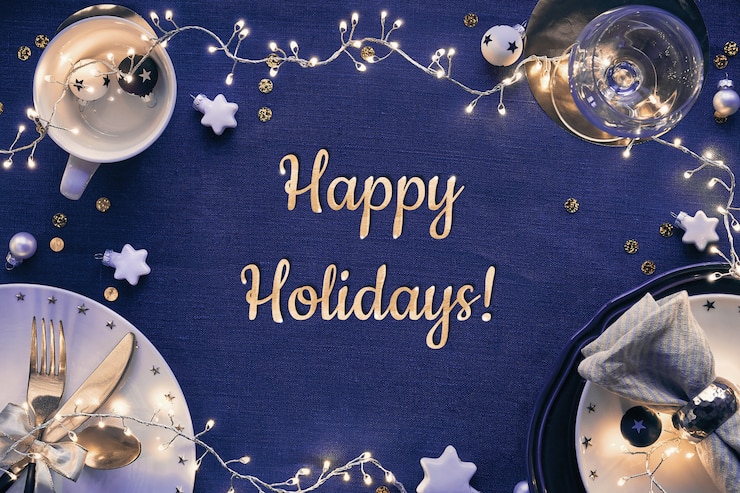 Photo text happy holidays. christmas table setup with white plates, golden utensils and dark red gilded decorations. flat lay, top view on dark blue linen textile.