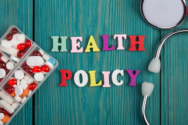 Text Health policy of colored wooden letters stethoscope and pills